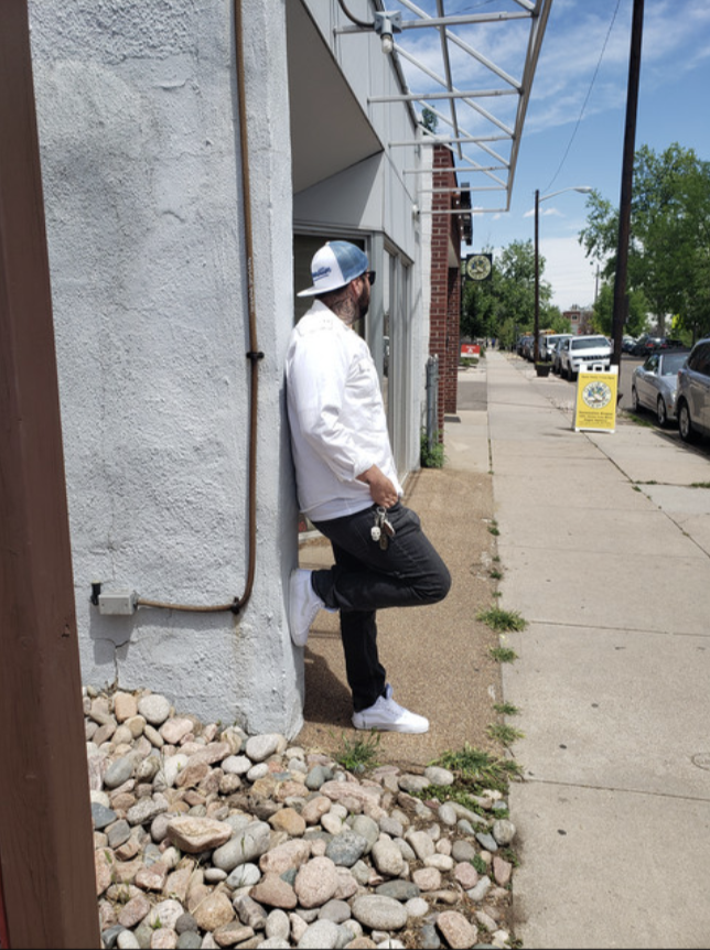 Cody P. leaning against a wall on a downtown sidewalk